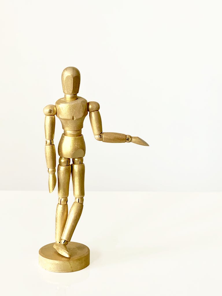 A wooden mannequin figure posed against a minimalist white background.