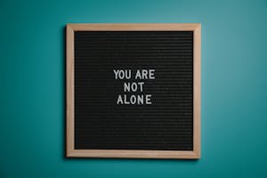 A wooden letter board displays a motivational message against a teal background.